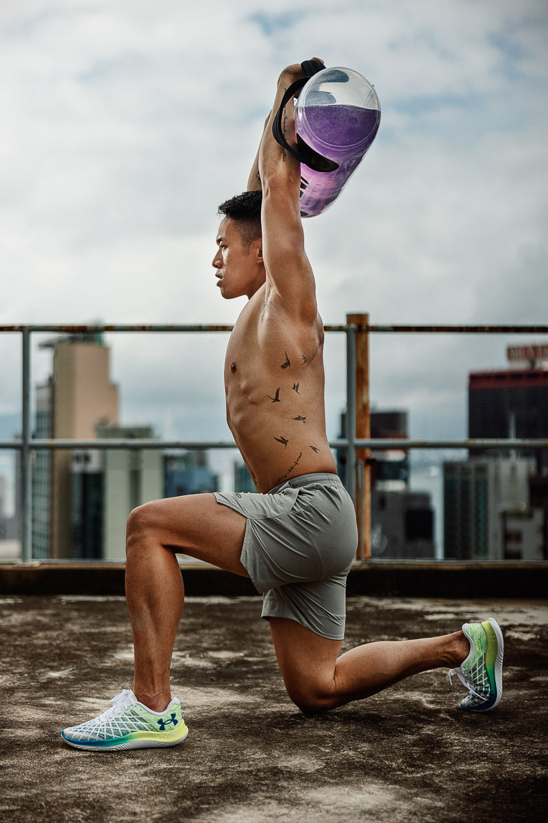 An advanced overhead shoulder stability drill showing an athlete holding a Fluid X Tank locked out overhead for return-to-sport training.